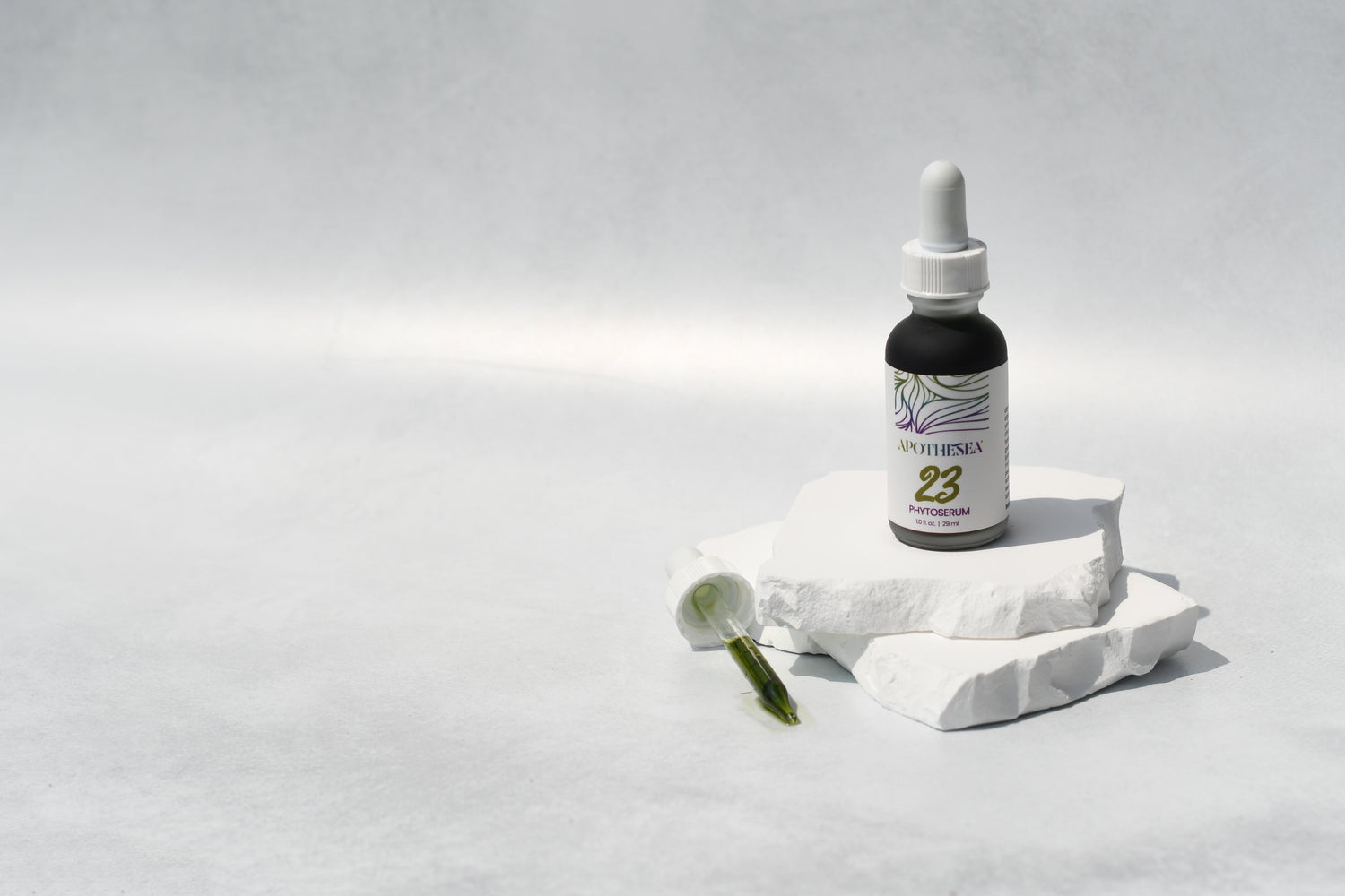 23 Phytoserum on white stone with dropper against grey background.