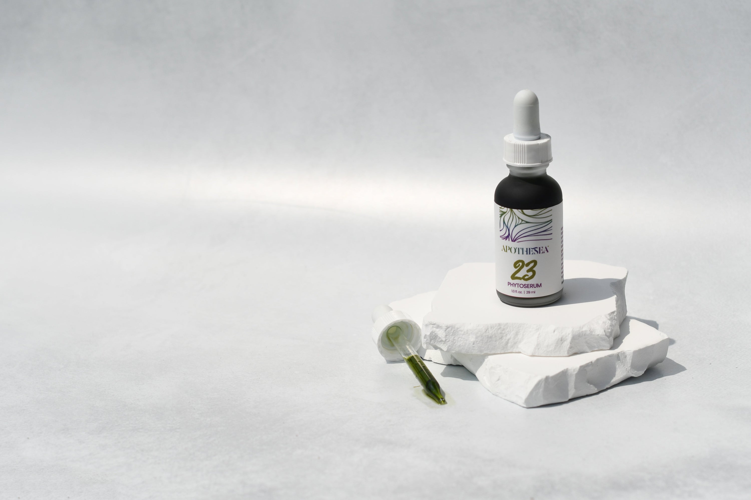 23 Phytoserum on white stone with dropper against grey background.